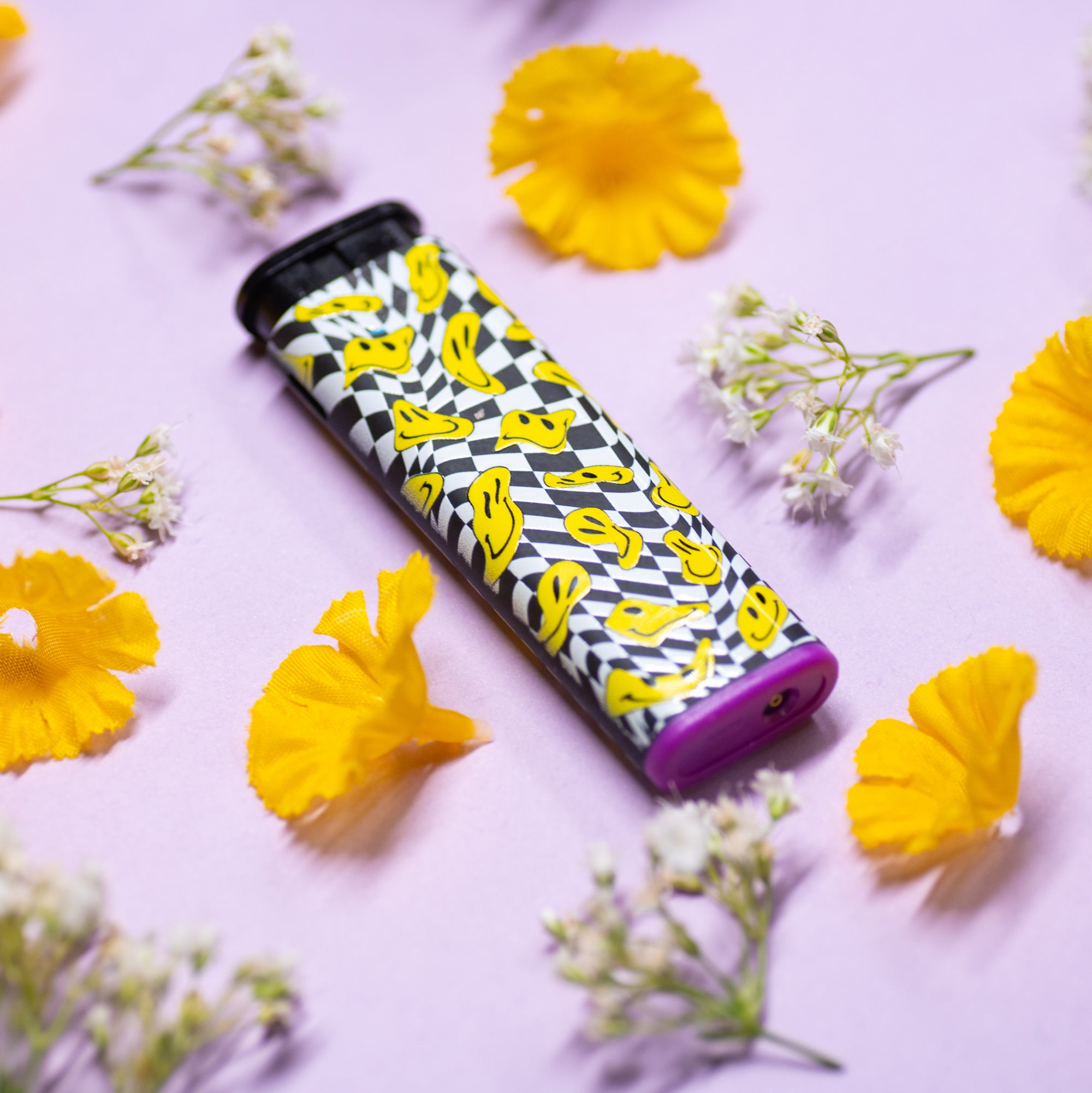 Trippy drooping yellow smiley faces on a black and white pattern torch lighter with purple accent on flower stylized background