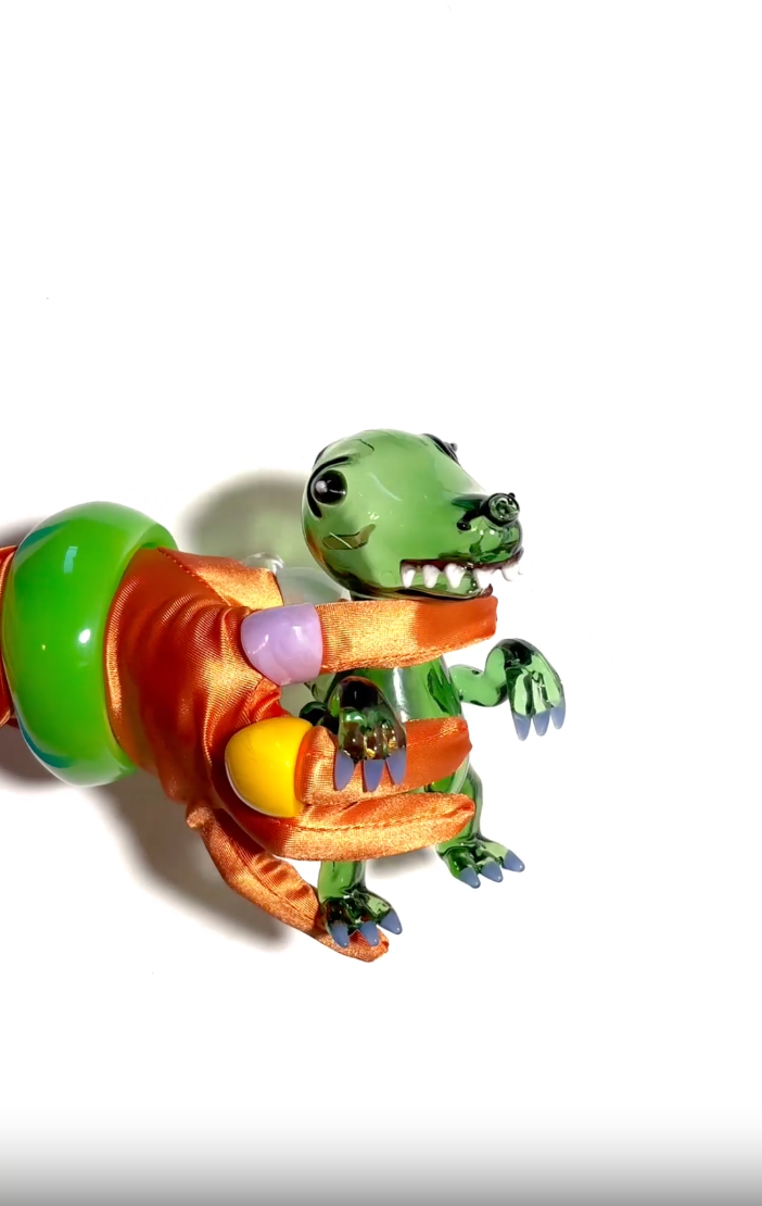 Green dinosaur with white teeth and blue claws glass bong on an orange hand with colorful gemstones on a white background video