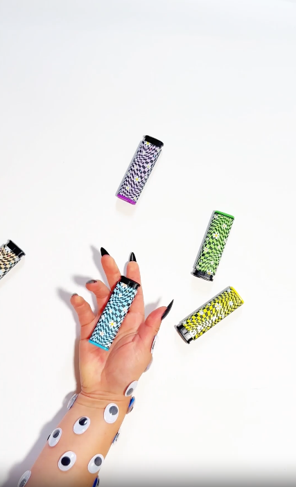 Hand with googly eyes playing with torch lighters with a daisy chain and block pattern video