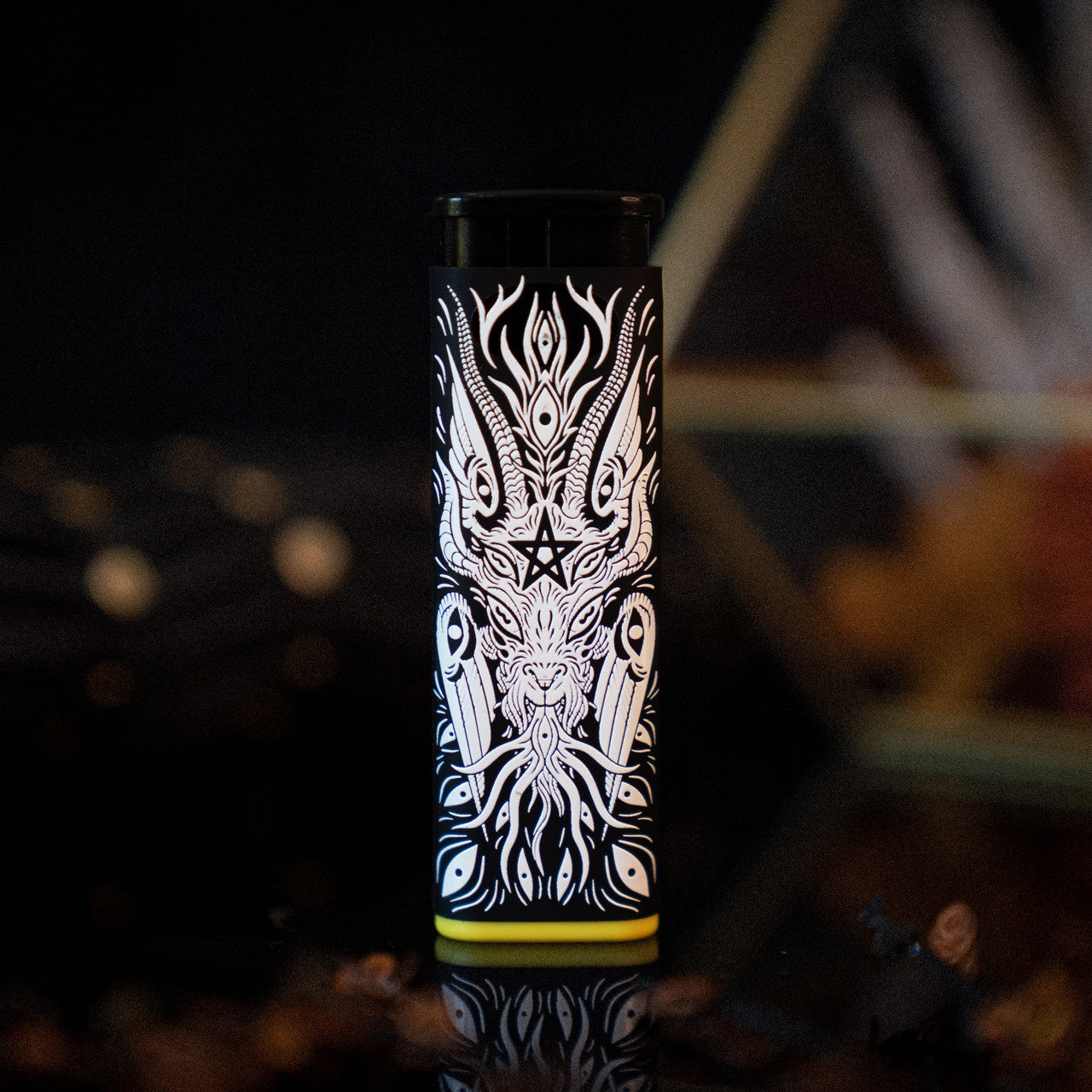 A black Baphomet Torch Lighter designed by XinaXiii with white line art of a headless figure with horns and yellow accent
